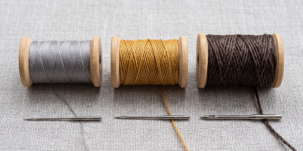 Comparaison de bobines de fil n°100, jeans et extra-fort avec l'aiguille machine adaptée à chacune