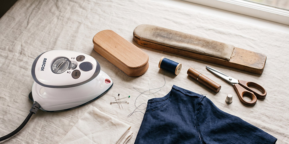 Atelier de couture : mini fer vapeur, jeannette, clapper en hêtre, coussin de repassage et pattemouille sur une table