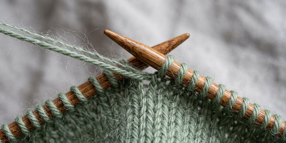 Un brin de mérinos et un brin de mohair-soie tricotés ensemble sur une aiguille en bois